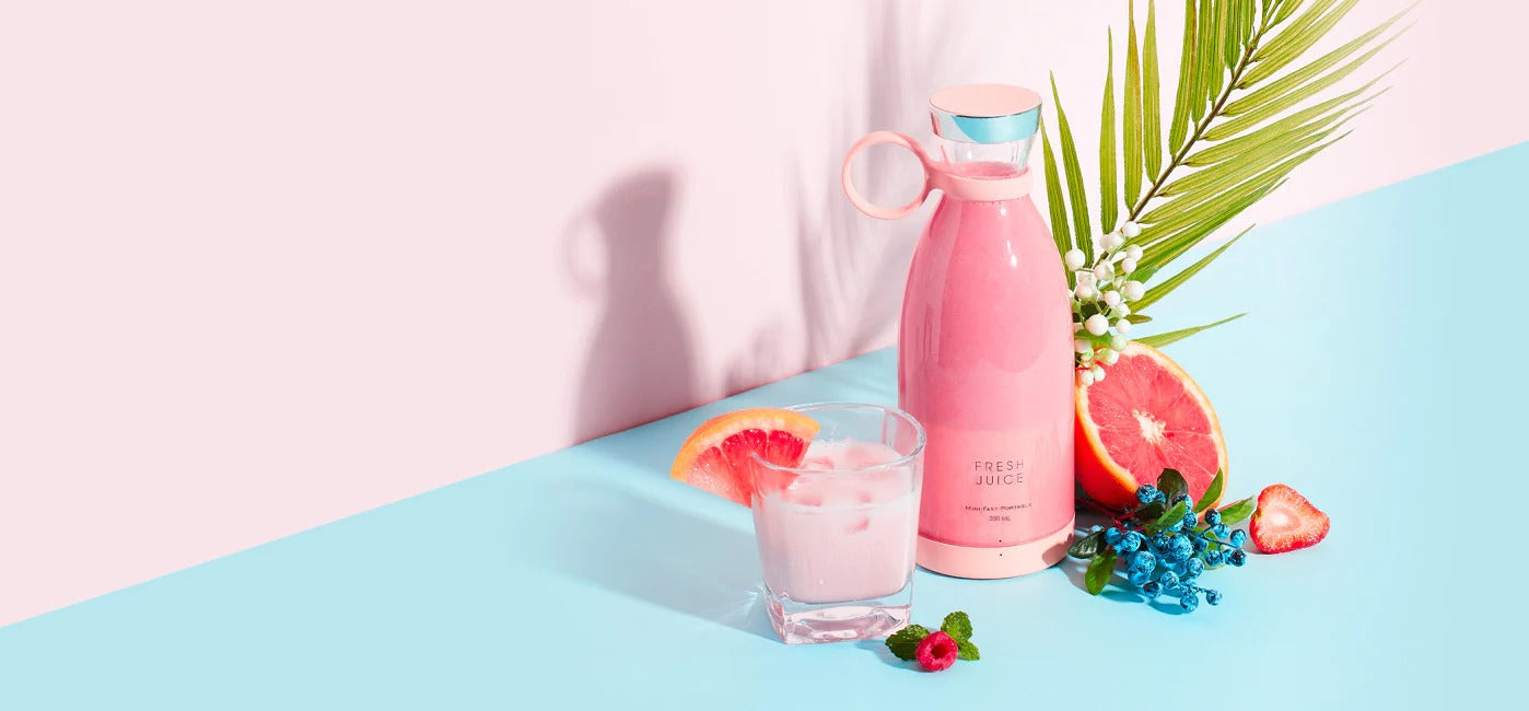 Pink water bottle and glass with pink drink on a pastel background